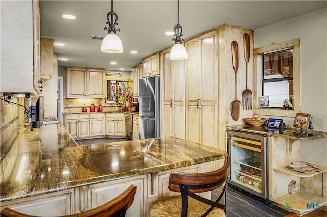 kitchen with appliances with stainless steel finishes, decorative light fixtures, dark stone countertops, beverage cooler, and light brown cabinets