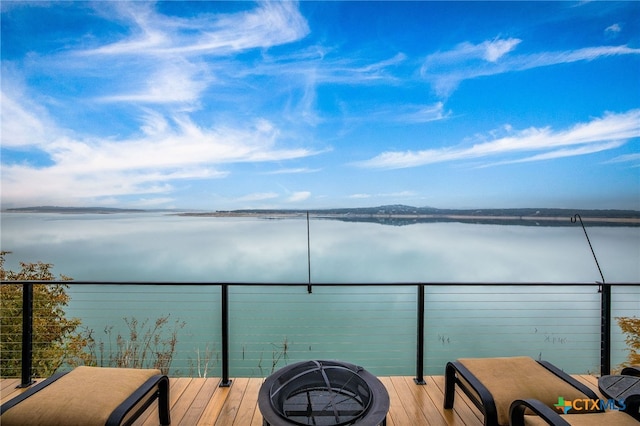 balcony with a water view and an outdoor fire pit