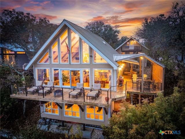 back house at dusk featuring a deck