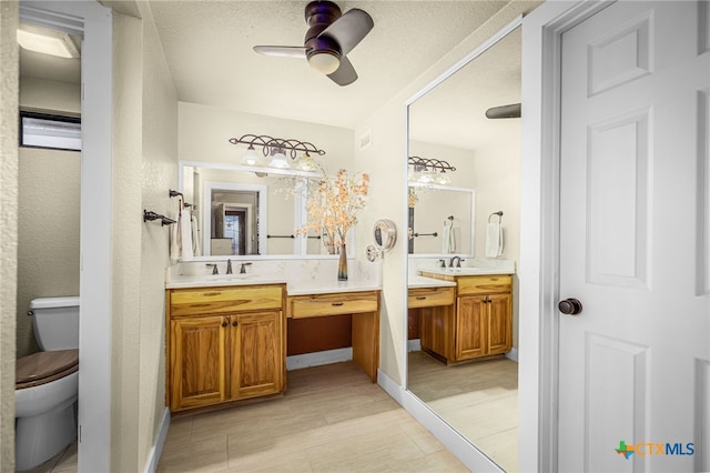 bathroom featuring vanity, a textured ceiling, ceiling fan, and toilet