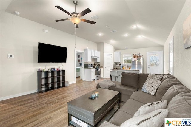 living room featuring light hardwood / wood-style flooring, lofted ceiling, and ceiling fan