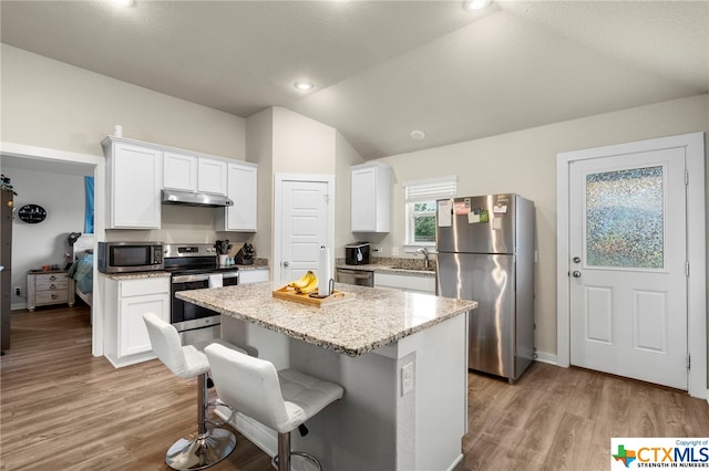 kitchen featuring a kitchen island, light wood-type flooring, appliances with stainless steel finishes, vaulted ceiling, and white cabinets