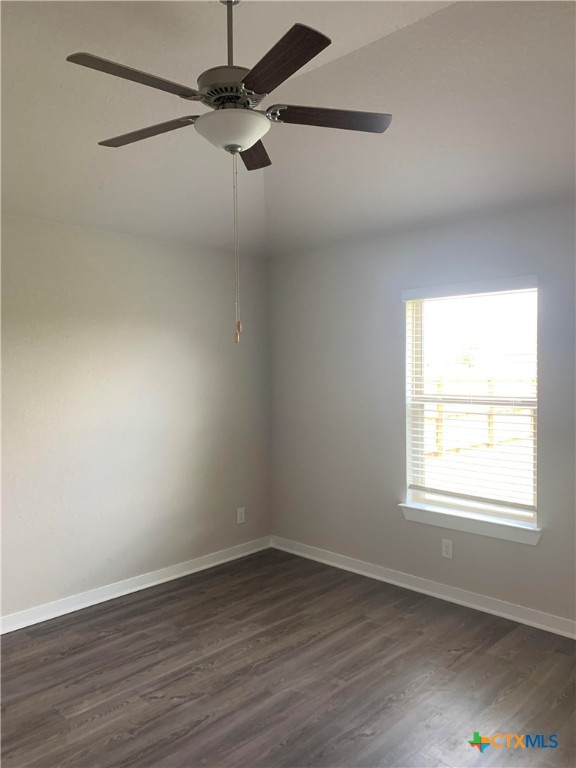 unfurnished room with ceiling fan and dark hardwood / wood-style flooring