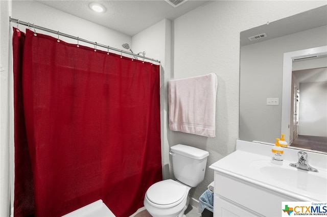 bathroom featuring curtained shower, vanity, and toilet