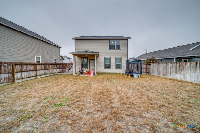 rear view of house with a trampoline and a lawn