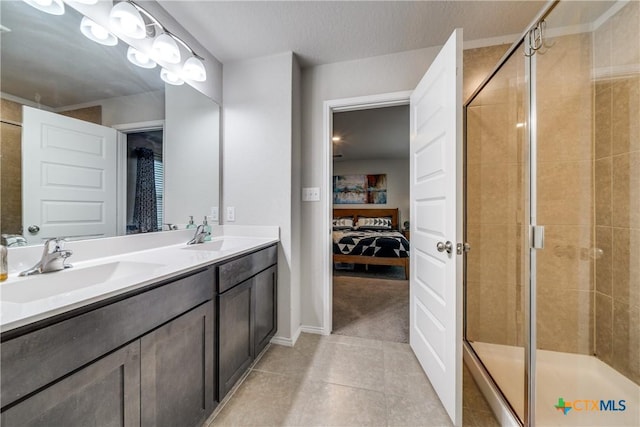 bathroom with tile patterned flooring, vanity, a shower with door, and a textured ceiling