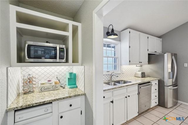 kitchen with stainless steel appliances, white cabinetry, light stone countertops, and sink