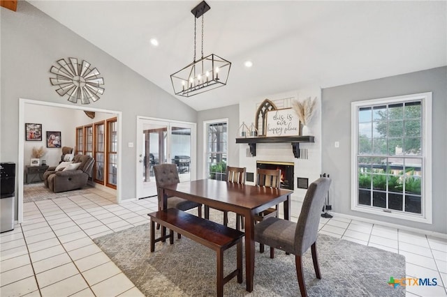 dining area with high vaulted ceiling, light tile patterned floors, a notable chandelier, and a fireplace