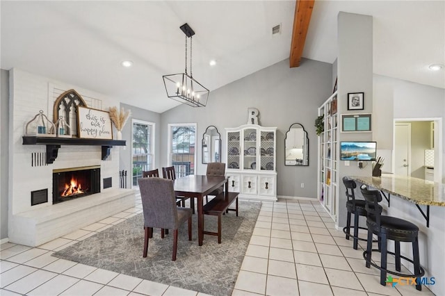 dining space with lofted ceiling with beams, a large fireplace, light tile patterned floors, and a notable chandelier