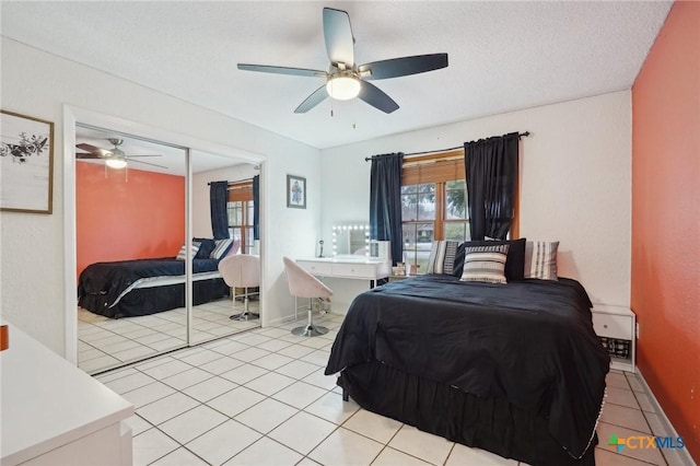 bedroom featuring a textured ceiling, a closet, ceiling fan, and light tile patterned flooring