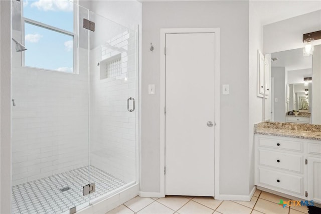 bathroom with walk in shower, vanity, and tile patterned flooring