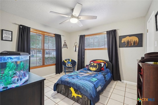 bedroom featuring ceiling fan, a textured ceiling, and light tile patterned floors