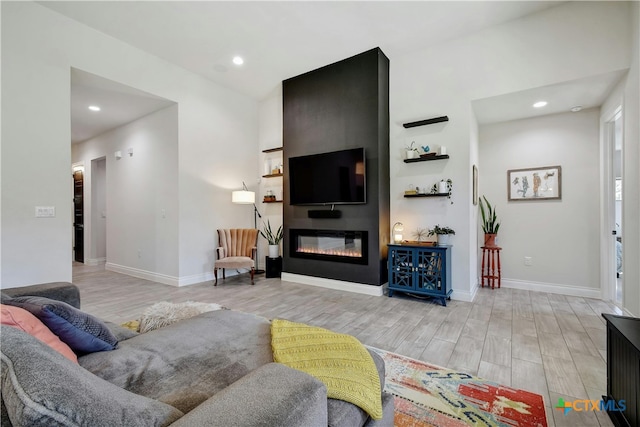 living room featuring light wood-type flooring and a large fireplace