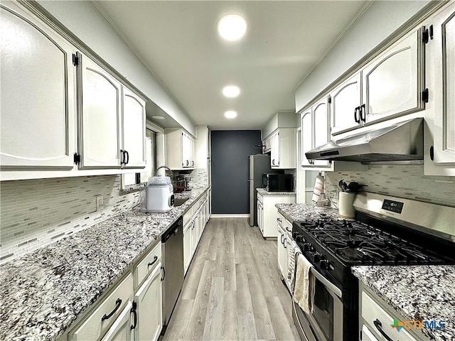 209 Roanoke Dr, Victoria, TX 77904 - kitchen with stainless steel appliances, under cabinet range hood, light wood finished floors, tasteful backsplash, and light stone countertops
