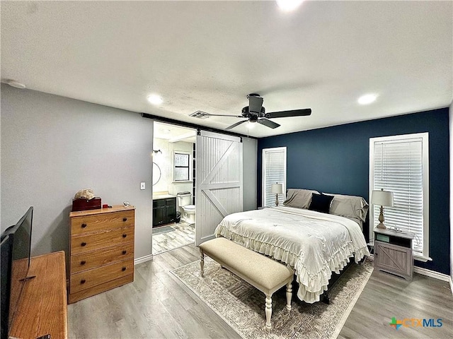 209 Roanoke Dr, Victoria, TX 77904 - bedroom with a barn door, light wood finished floors, ensuite bathroom, recessed lighting, and multiple windows