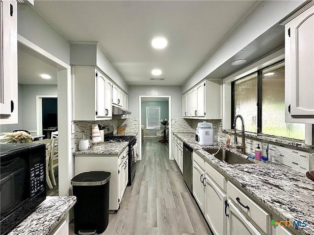 209 Roanoke Dr, Victoria, TX 77904 - kitchen with gas stove, black microwave, white cabinetry, and stainless steel dishwasher