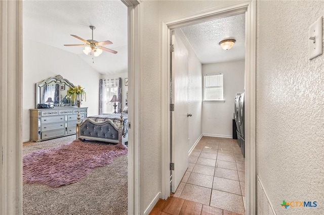 709 Aries Ave, Killeen, TX 76542 - hallway featuring a textured ceiling, a textured wall, washing machine and dryer, baseboards, and lofted ceiling