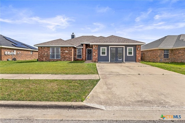 709 Aries Ave, Killeen, TX 76542 - view of front of property featuring french doors, a front yard, driveway, a chimney, and brick siding
