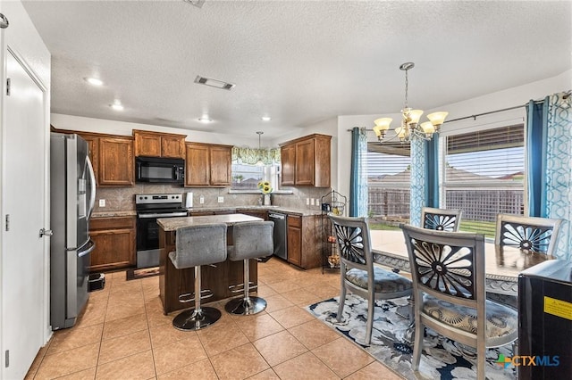 709 Aries Ave, Killeen, TX 76542 - kitchen with stainless steel appliances, a chandelier, decorative backsplash, a center island, and brown cabinets