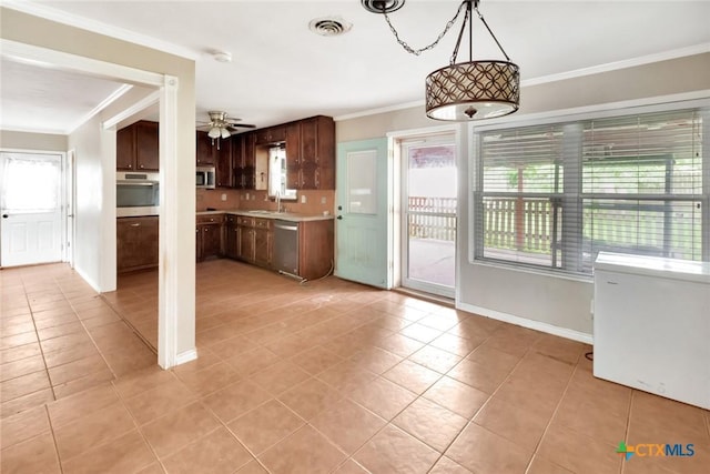 3106 Bobolink St, Victoria, TX 77901 - kitchen with stainless steel appliances, light tile patterned floors, healthy amount of natural light, ornamental molding, and light countertops