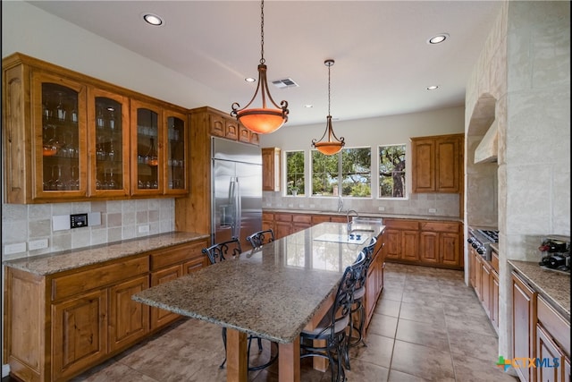 1280 Mystic Pkwy, Spring Branch, TX 78070 - kitchen featuring appliances with stainless steel finishes, brown cabinets, recessed lighting, decorative backsplash, and a center island with sink