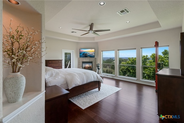 1280 Mystic Pkwy, Spring Branch, TX 78070 - bedroom with a tray ceiling, dark wood-style flooring, a glass covered fireplace, recessed lighting, and ceiling fan