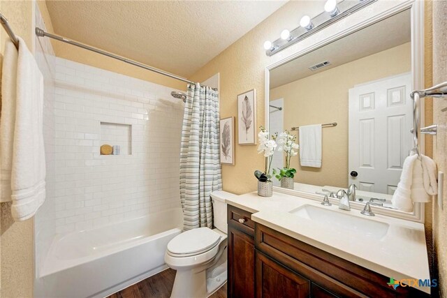 133 Ridgewood Cv, Georgetown, TX 78633 - bathroom featuring shower / bath combo with shower curtain, wood finished floors, vanity, a textured ceiling, and toilet