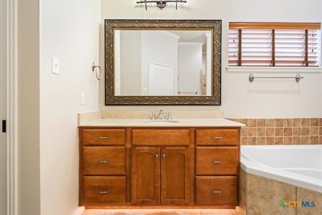 bathroom with vanity, crown molding, and tiled tub