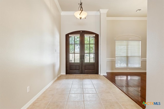 foyer with light wood-type flooring, french doors, and crown molding