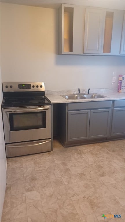 kitchen with a sink, light countertops, stainless steel electric range, and gray cabinetry