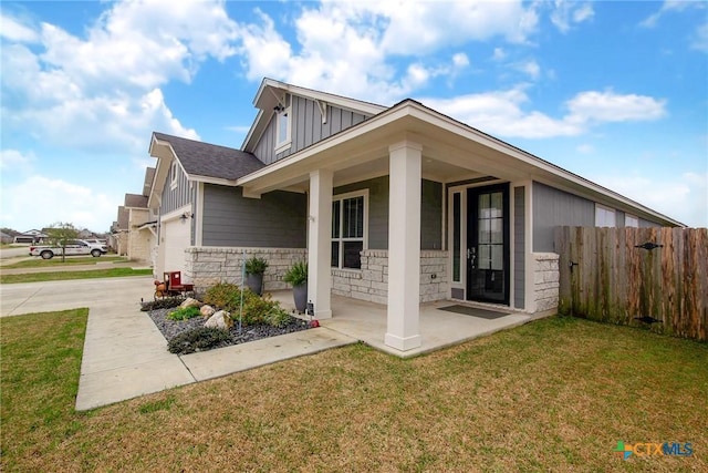 view of home's exterior with a garage, fence, stone siding, a lawn, and board and batten siding