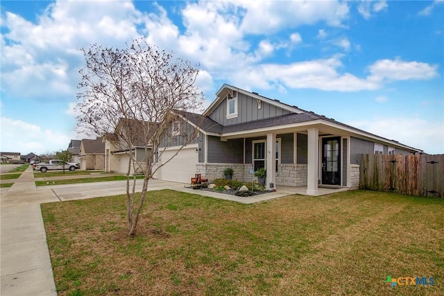 view of front of house featuring concrete driveway, stone siding, fence, a front lawn, and board and batten siding