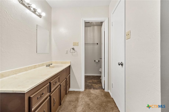 bathroom featuring baseboards, toilet, and vanity