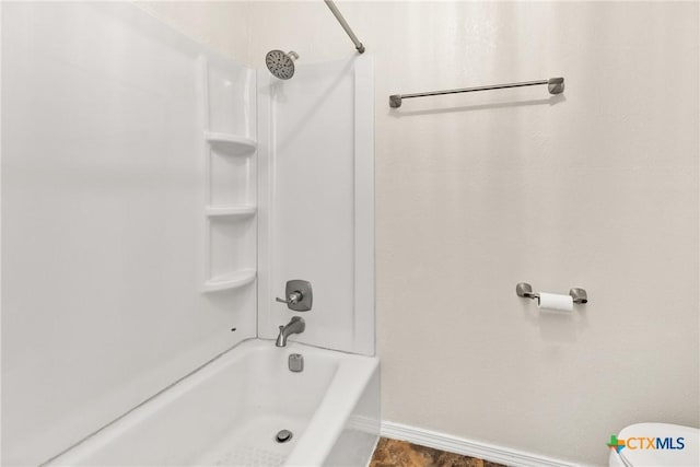 bathroom with tub / shower combination, toilet, and baseboards