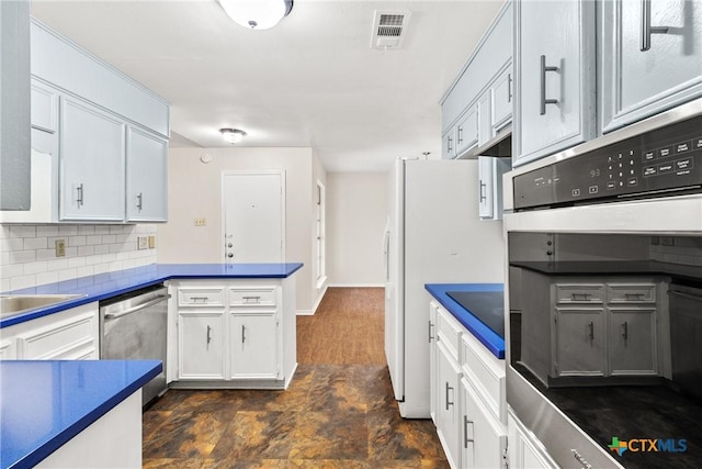 kitchen with visible vents, dark countertops, stainless steel appliances, a peninsula, and decorative backsplash