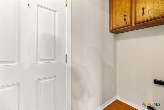 laundry room featuring dark wood-type flooring, cabinet space, and baseboards