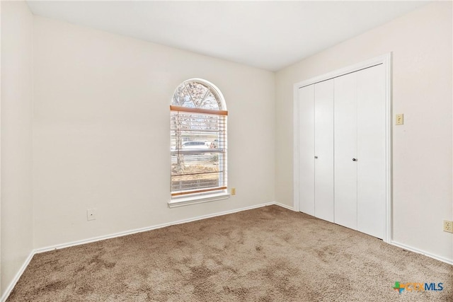 unfurnished bedroom featuring a closet, carpet flooring, and baseboards