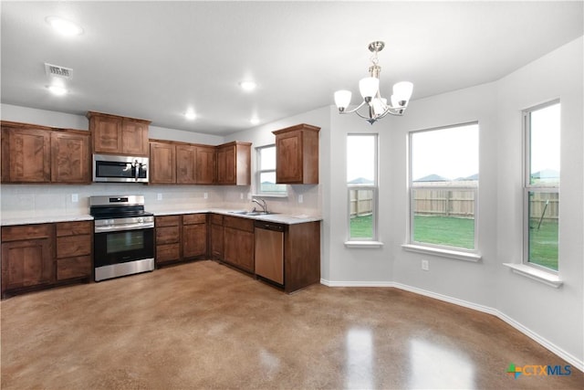 kitchen featuring tasteful backsplash, a sink, light countertops, a chandelier, and stainless steel appliances