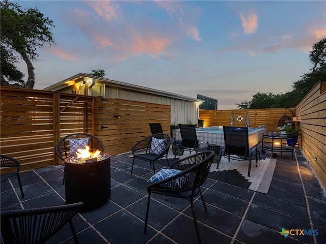patio terrace at dusk featuring a fenced backyard and an outdoor fire pit