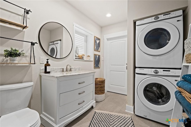 laundry area featuring recessed lighting, stacked washer and dryer, a sink, and laundry area