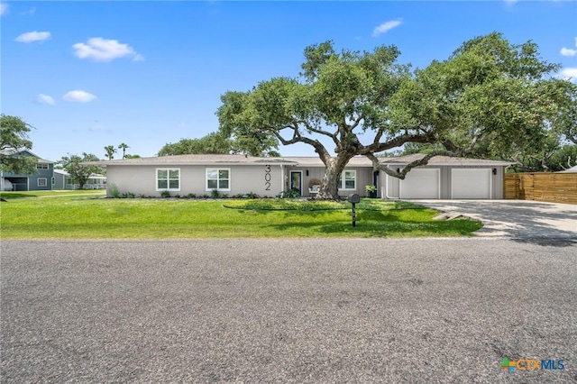 view of front of property with fence, an attached garage, a front lawn, and driveway