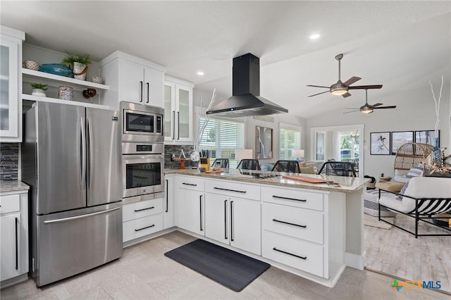 kitchen with wall chimney range hood, a ceiling fan, a peninsula, tasteful backsplash, and appliances with stainless steel finishes