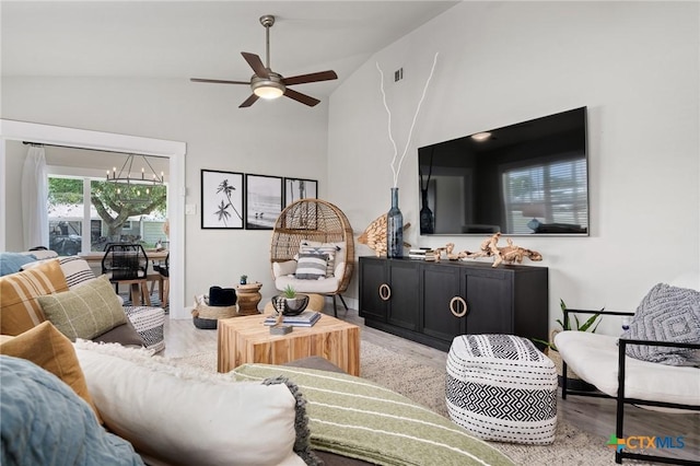 living room with light wood-type flooring, visible vents, high vaulted ceiling, and ceiling fan with notable chandelier