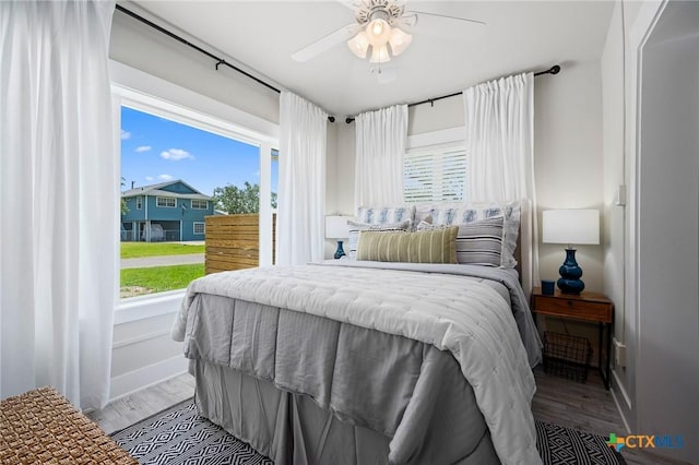bedroom with baseboards, multiple windows, and wood finished floors