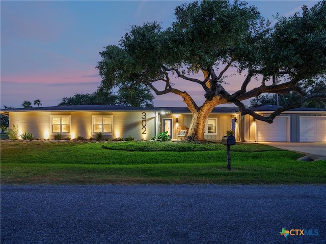 single story home featuring an attached garage, a front yard, and concrete driveway