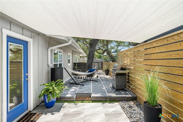 view of patio with fence, grilling area, and a storage shed