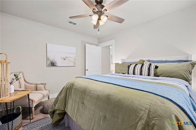 bedroom featuring wood finished floors, visible vents, baseboards, and ceiling fan