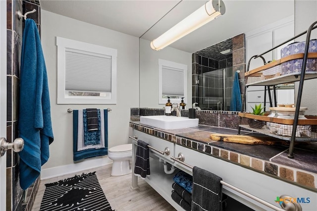full bathroom with toilet, a stall shower, baseboards, wood finished floors, and vanity