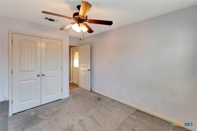 unfurnished bedroom with ceiling fan, a closet, and light carpet