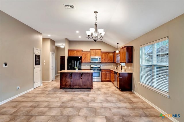 kitchen with sink, a center island, vaulted ceiling, hanging light fixtures, and stainless steel appliances